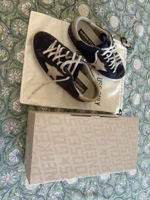 Golden Goose Superstar - Snygga mörkblå sneakers från Golden Goose med vit stjärndetalj på sidan och vita skosnören. Skorna är tillverkade i mocka med detaljer i läder. Skorna är Köpta från cettire.