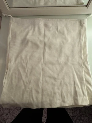 Vit ribbad tubtopp från Nelly - Säljer en enkel och stilren vit ribbad tubtopp från Nelly. Toppen är axelbandslös och har en mjuk, stretchig känsla som sitter snyggt på kroppen. Perfekt att matcha med jeans eller kjol för en clean look.