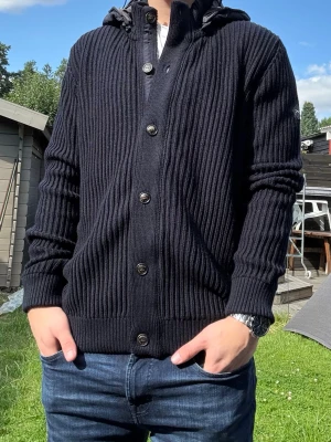Stickad ull cardigan  - Riktigt fin stickad cardigan med avtagbar luva i ullblandning . Storlek 52, sitter som M. Passar om du är mellan 180-190 ish. Mycket fint skick.