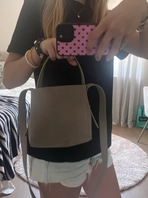Beige minihandväska med axelrem - Snygg beige minihandväska i stilren design med både handtag och lång axelrem💕. Väskan har en fyrkantig form och är gjord i ett mjukt material som ser ut som mocka eller skinnimitation. Perfekt för dig som gillar minimalistisk och trendig stil.💕💕
