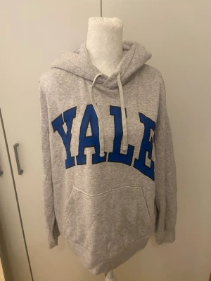 Grå hoodie - Säljer en grå hoodie från H&M med blå text: YALE. Storlek S. Mycket bra skick.