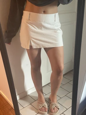 Vit kortkjol med slits - Snygg vit kort kjol/skort i storlek L har dragkedja vid sidan, Aldrig använd 💕
