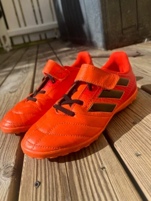Adidas Ace 17.4 TF fotbollsskor / grusskor (Strl 35) - Säljer ett par superfina Adidas Ace 17.4 TF (Turf) fotbollsskor för barn i en cool och synlig orange färg.   Skorna har en praktisk och smidig stängning med kardborreband samt elastisk fejk-snörning, vilket gör dem väldigt enkla för barnet att ta på och av själv.  TF-sulan har små gummibubbar som ger ett perfekt grepp på både konstgräs, grus och tuffare utomhusytor.