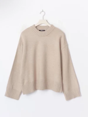 Beige stickad tröja från Gina Tricot - Mysig beige stickad tröja från Gina Tricot med rund halsringning och breda ribbade muddar vid ärmslut och nederkant. Köpt för kanske 400 oanvänd