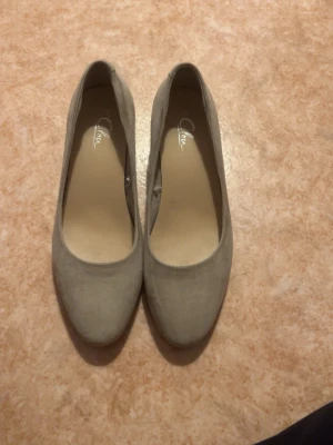 Beige pumps med låg klack - Snygga beige pumps med rund tå och låg, bred klack. Skorna har en stilren design och är tillverkade i ett mockaliknande material. Perfekta för dig som vill ha både stil och komfort. Passar till många olika outfits. Aldrig använt 