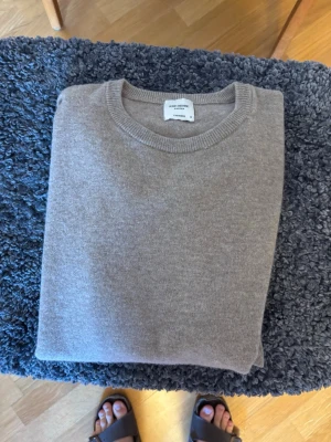 Beige cashmere-tröja med rund hals John Henric - Snygg och stilren beige stickad tröja i cashmere från John Henric. Tröjan har rund halsringning och ribbade muddar vid ärmslut och nederkant. Perfekt för dig som gillar en klassisk och mjuk look. 100% cashmere.