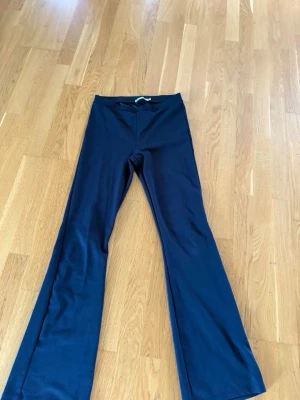 Svarta bootcut leggings - Säljer ett par svarta leggings med bootcut-ben och hög midja. De är stretchiga men ser ut som kostymbyxor material och har en enkel, stilren design utan synliga fickor eller detaljer. Perfekta för dig som gillar en bekväm men trendig look.