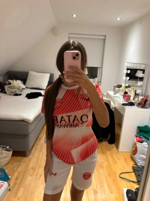 PSG matchställ röd/vit Nike -  Säljer ett PSG matchställ från Nike med röd och vit tröja med grafiskt mönster och Qatar Airways-tryck. Tillhörande vita shorts med PSG-logga och röd Nike-swoosh. Perfekt för fotbollsträning eller match.