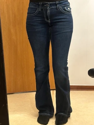 Gina tricot Young Mörkblå y2k bootcut jeans - Snygga mörkblå bootcut-jeans med vita kontrastsömmar och klassisk femficksdesign. Låg midja och lätt utsvängda ben. Storlek 164 från Gina Young, passar perfekt på mig som är 159 cm. Endast använda max 4 gånger och är i nyskick! Inga fläckar, märken eller annat. Väldigt fint och fräscht skick, hoppas de kan få ett nytt fint hem 💕💕
