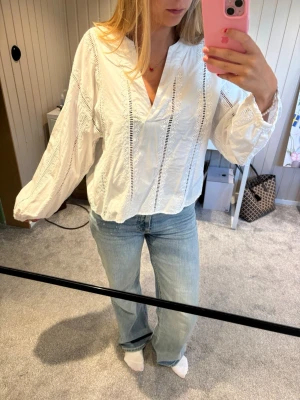 Vit blus med spetsdetaljer från Zara - Säljer en luftig vit blus från Zara med snygga spetsdetaljer och v-ringning. Blusen har långa ärmar. Aldrig använd.
