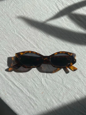 Solglasögon i leopardmönster - Snygga smala solglasögon med leopardmönstrad båge i bruna och svarta toner. 
