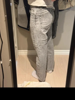 Grå raka jeans med tvättad look - Säljer ett par grå jeans med tvättad effekt och raka ben. Jeansen har klassisk femficksmodell, normal passform och stängs med dragkedja och knapp. Perfekta till en avslappnad stil och passar till det mesta.