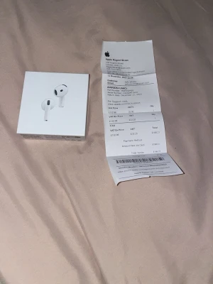 Apple AirPods 4 med laddningsetui - Säljer ett par vita Apple AirPods 4 med trådlöst laddningsetui. Snygg och kompakt design i blank plast, perfekt för dig som vill ha smidiga hörlurar till mobilen. Levereras i originalförpackning.