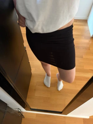 Svart tight kortkjol - En enkel och stilren svart tight kjol i kort modell. Kjolen har en rak passform och är perfekt att matcha med en oversized t-shirt eller crop top. Materialet känns mjukt och stretchigt vilket gör den bekväm att bära. Skriv pm vid funderingar!☺️