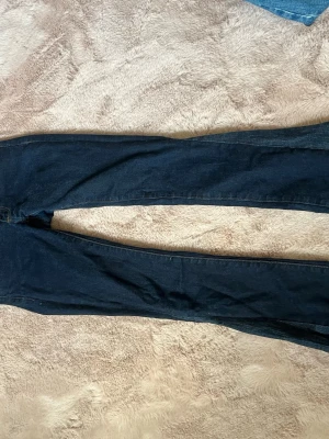Mörkblå jeans från Crocker - Säljer ett par mörkblå jeans från Crocker med klassisk femficksmodell och kontrastsömmar i gult. Jeansen är botcut och är omsydda som visas på bilden om man behöver mått är det Beata att skriva 