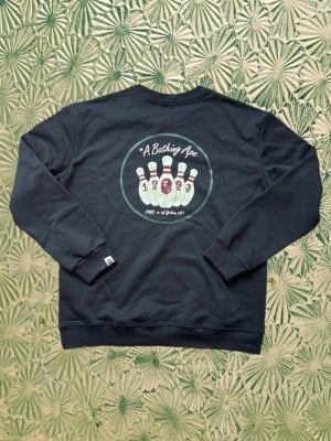 Svart sweatshirt Bape - Riktigt snygg svart sweatshirt från Bape i storlek L, med snyggt tryck framtill. Skön passform och sitter riktigt bra på. En riktigt fet piece som ger starka archive/vintage-vibbar.