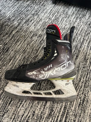 Bauer Vapor Hyperlite skridskor - Säljer ett par Bauer Vapor Hyperlite hockeyskridskor i svart, vitt och gult. Skridskorna har en modern design med högt skaft, gula snören och detaljer i rött på plösen. Perfekta för dig som vill ha snabba och lätta skridskor på isen.
