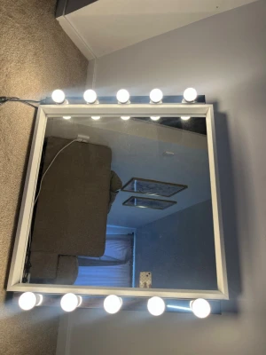Sminkspegel med LED-lampor, vit ram - Snygg sminkspegel med vit ram och tio LED-lampor runt spegeln som ger perfekt belysning för sminkning. Spegeln är fyrkantig och har en modern look som passar i de flesta rum. Perfekt för att fixa sminket med bra ljus.