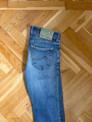 Jacob Cohen jeans - Snygga Jacob Cohen jeans med raka ben och diskreta slitningar framtill. Klassisk femficksmodell med detaljerad bakficka och patch på linningen. Perfekta för en avslappnad och trendig look.