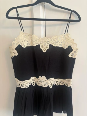 Viral Zara topp - Supersöt svart linnetopp med tunna axelband och dekorativa vita spetsdetaljer upptill och i midjan. Toppen har en flowy passform och är perfekt för en trendig och feminin look. Spetsen ger en romantisk touch och toppen är lätt och luftig. Helt ny helt slutsåld överallt 