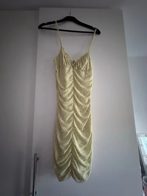 Ljusgul blommig klänning - Ljusgul klänning från H&M Divided med smala axelband och blommigt mönster. Klänningen är figursydd med kort längd. Använd ett fåtal gånger.