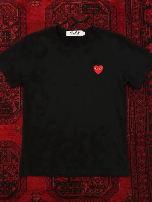  Comme des Garçons PLAY t-shirt - Svart t-shirt från Comme des Garçons PLAY med det ikoniska röda hjärtat med ögon broderat på bröstet. Klassisk rund hals och korta ärmar. Tillverkad i mjuk bomull för en skön och stilren look.