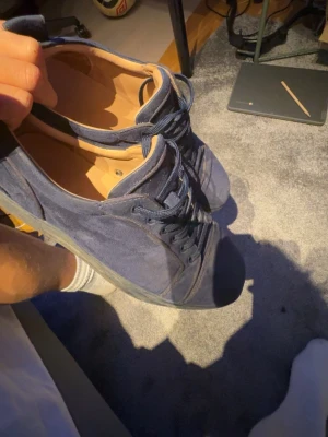 Christian Louboutin - Säljer ett par mörkblå sneakers i mocka med matchande snören och sula. Skorna har en låg profil och broderad text på hälen. Insidan är ljusbeige och de har en klassisk, stilren look som passar till det mesta. Pris ej hugget i sten, dom är smutsig men kan fixas innan skickning. 