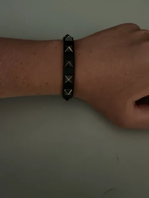 Valentino armband  - Snyggt svart armband i läder med silverfärgade pyramidformade nitar längs bandet. Armbandet har ett spänne i metall för justerbar passform och ger en cool och edgy vibe till din stil. Pris kan sänkas via snabb affär mvh EJ!
