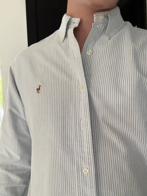 Randig skjorta från Ralph Lauren - Säljer en vintage men nästan oanvänd Ralph Lauren skjorta i vitblåa ränder. Den är i toppenskick sitter jätteskönt. Materialet är bra och skjortan är tvättad utan fläckar eller hål.