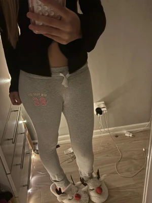Gråa mjukisbyxor med tryck - Passar mig som 155 cm lång🤍Snygga grå mjukisbyxor med vitt knytband i midjan och trycket 'New York 86' i vitt och rosa på ena benet. 