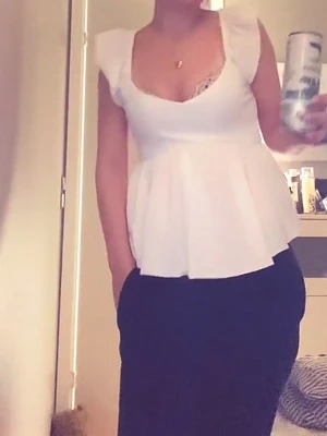Vit peplum topp med volang - Snygg vit peplum topp med volangkant och djup v-ringning. Toppen har breda axelband och är ärmlös, vilket ger en fräsch och feminin look. Perfekt att styla med både jeans och kjol för en trendig outfit.