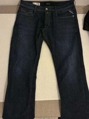 Mörkblå jeans från Replay - Snygga mörkblå jeans från Replay med klassisk femficksmodell och raka ben. Jeansen har kontrastsömmar och en liten logotyp på bakfickan. Tillverkade i slitstarkt denimtyg som ger en tidlös look. Dessa byxor har storleken W36 och L32
