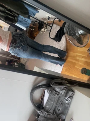 Miss me jeans - Säljer ett par blå bootcut jeans med snygga kontrastsömmar och detaljerade bakfickor. Jeansen har låg midja och klassisk femficksdesign. Materialet är denim med lätt tvättad look och slitningar för en trendig vibe.