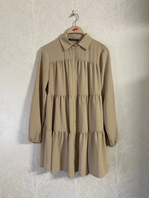 Beige Boohoo Volangklänning  - Säljer en beige volangklänning från Boohoo som når ner till knäna.   Längd: ca 83 cm. Axelbredd: ca 38 cm.