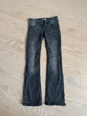 Svarta bootcut jeans från Gina Tricot - Snygga svarta bootcut jeans från Gina Tricot i storlek 152. Jeansen har en klassisk femficksmodell, knappgylf och lätt slitna detaljer framtill för en cool look. Perfekta till vardagsstilen och passar till det mesta.