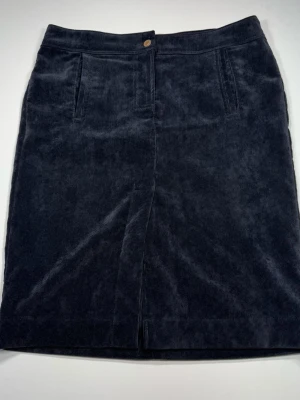 Armani Jeans Mörkblå manchesterkjol med fickor - Snygg mörkblå kjol i manchester från Armani Jeans med raka linjer och klassisk passform. Kjolen har fickor fram och bak, samt dekorativa knappar bak. Perfekt för dig som gillar en stilren och tidlös look. 0049