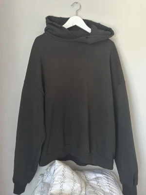 Svart hoodie Acne Studios - Säljer en svart hoodie från Acne Studios med stor huva och tryck på ryggen där det står 'Acne Studios STOCKHOLM 1996' i vitt. Hoodien har avslappnad passform, långa ärmar och ribbade muddar. Perfekt för en chill och stilren look.