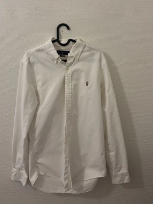 Vit skjorta från Ralph Lauren Slim Fit - Klassisk vit skjorta från Ralph Lauren i modellen Slim Fit. Den är använd endast 1 gång och är i ett otroligt bra skick, kontakta för mer information 