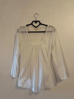 Vit tunn blus  - Söt vit blus med romantisk känsla och rynkad ringning. Blusen har trekvartsärmar och är gjord i ett tunt, lätt material som ger ett luftigt intryck. 