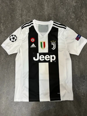 Juventus Champions League 18/19 - Som ny Juventus fotbollströja med Ronaldo #7  Tröjan är endast använd en gång och är i mycket fint skick, som ny. Inga skador eller fläckar.  Pris: 400 kr – tycker det är ett bra och rimligt pris för tröjan. Priset kan diskuteras vid snabb affär.  Skickas snabbt och packas ordentligt.