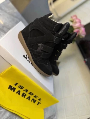 Svarta sneakers Isabel Marant - Säljer ett par svarta sneakers från Isabel Marant med högt skaft och coola kardborreband. Skorna är gjorda i mocka och läder med en brun gummisula. Perfekta för dig som vill ha en edgy och trendig look.