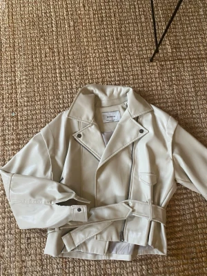 Skinnjacka  - Supertrendig vit/ljusbeige skinnjacka ifrån Stradivarius, storlek S! Mycket bra skick, knappt använd! 