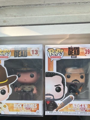 Funko Pop! The Walking Dead figurer - Två Funko Pop! vinylfigurer från The Walking Dead: Rick Grimes (#13) och Negan (#390). Båda är i originalförpackning med tydliga detaljer och färger. Perfekt för samlare eller fans av serien. Helt oöppnad och har kvar sitt värde.