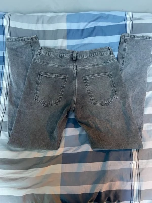 Grå Slim fit jeans - Säljer ett par grå jeans med raka ben och hög midja. Klassisk femficksmodell med två bakfickor och bälteshällor. Jeansen har en tvättad look och är tillverkade i denim, perfekt för en avslappnad stil.