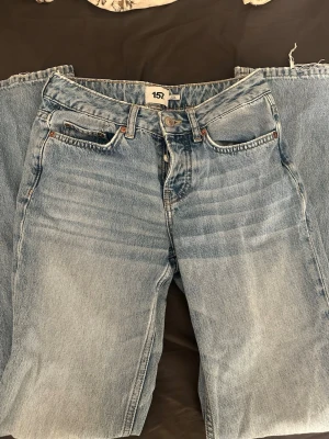 Ljusblå raka jeans från 157 - Säljer ett par ljusblå jeans från 157 med rak passform och klassisk femficksdesign. Jeansen har en snygg tvättad look och silverfärgad knapp. Perfekta för en avslappnad och trendig stil.