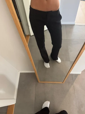 Svarta lågmidjade kostymbyxor - Säljer ett par svarta lågmidjade kostymbyxor med rak passform och pressveck. Byxorna har hällor för skärp och sidofickor. Klassisk look som funkar till många olika stilar. Materialet ser ut att vara en blandning av polyester och viskos. Använda 1 gång, säljer för att de är för långa. Nypris 499 kr
