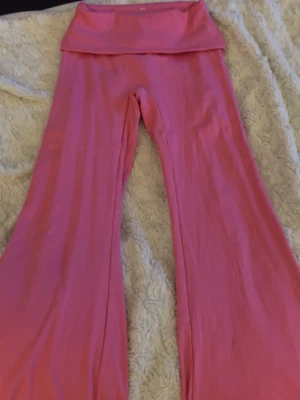 Rosa bootcut leggings från Peach - Säljer ett par rosa leggings från Peach i bootcut-modell. De har hög midja och är tillverkade i mjuk bomull med lite stretch (90% bomull, 10% spandex). Perfekta för en avslappnad och trendig look.