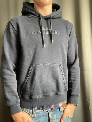 J.Lindeberg hoodie, strl S - Säljer en fin hoodie från J.Lindeberg i mörkblå färg. || Mycket bra skick, lite urtvättad.    Storlek: L men sitter mer som en S || modellen på bilden är 178cm och 70kg || Självklart äkta och skickar inom 24h efter köp! Hör av er vid minsta fundering🤝