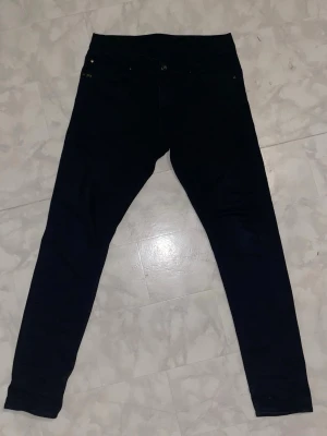 Svarta Tiger Of Sweden Jeans - Snygga svarta jeans med klassisk femficksdesign och smal passform. Jeansen har hög midja och stretchigt material som sitter tajt längs benen. Perfekta för en trendig och avslappnad look.