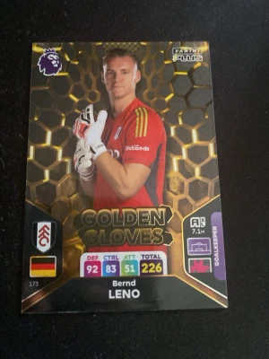 Golden Gloves Bernd Leno spelkort - Samlarkort från Panini Plus med Bernd Leno i Fulham FC, Golden Gloves-edition. Kortet har svart och guld bakgrund, med Leno i röd målvaktströja och vita handskar. Kortet visar stats och klubbmärke samt tysk flagga.